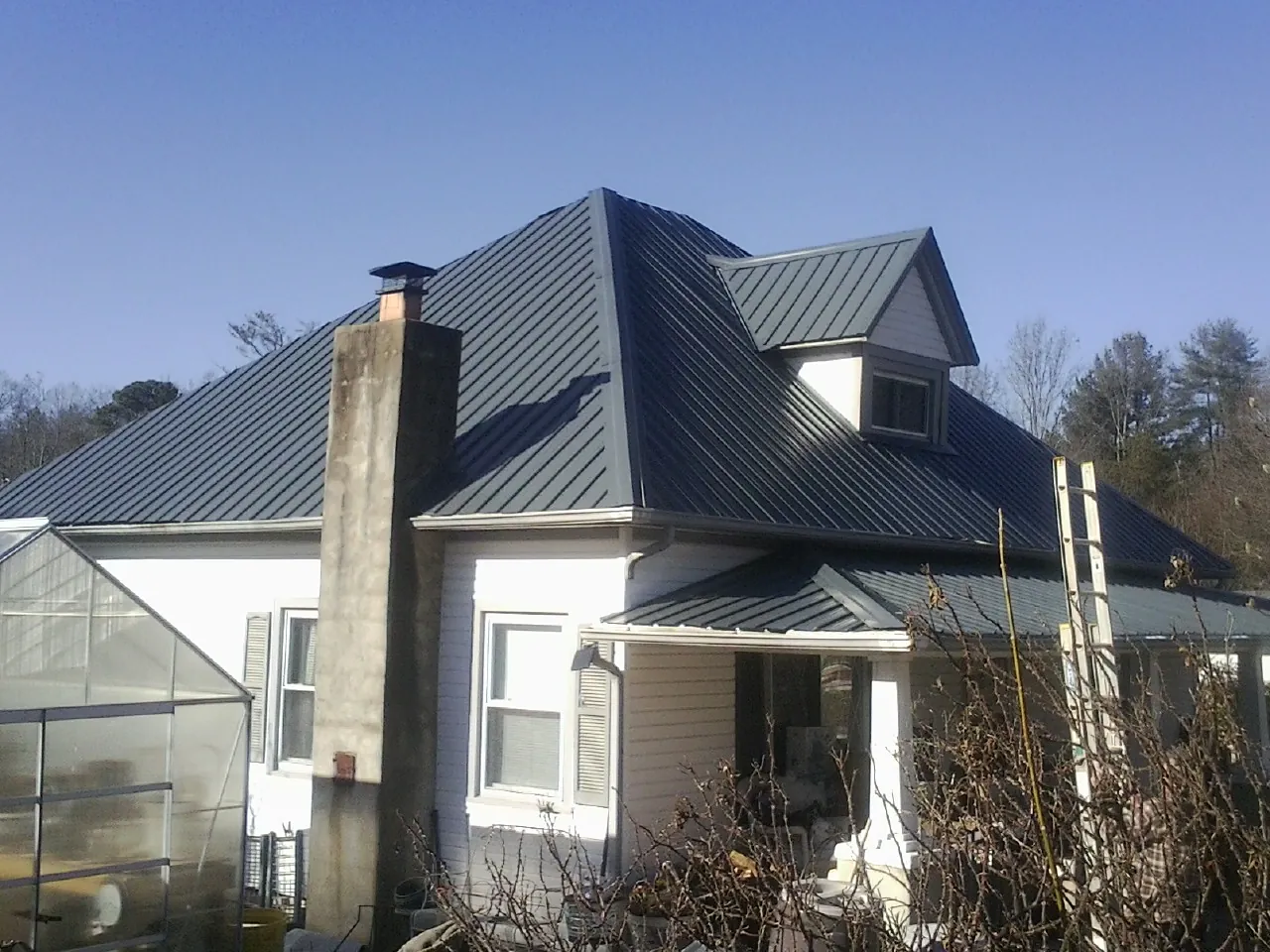 Dark blue standing seam metal roof on a white farmhouse with dormer — Slate & Tile Roof Repair by Roofing Brothers in Hermanville