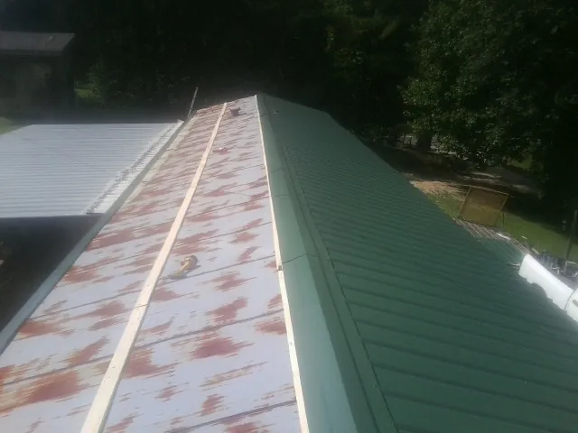 Old rusted panels beside newly installed green metal roofing — Wind Damage Roof Repair by Roofing Brothers in Hermanville