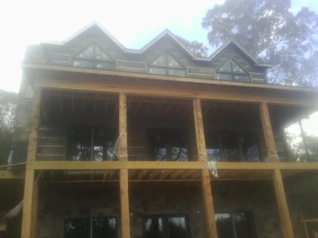 Dormers and porch framing on a large log home under construction — Roof Coating work by our crew in Hermanville