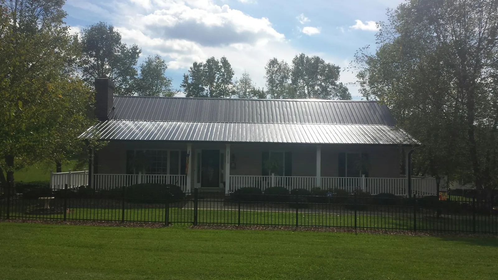 Gray metal roof on a brick ranch with a full width front porch — Gutter Guard Installation work by our crew in Hermanville