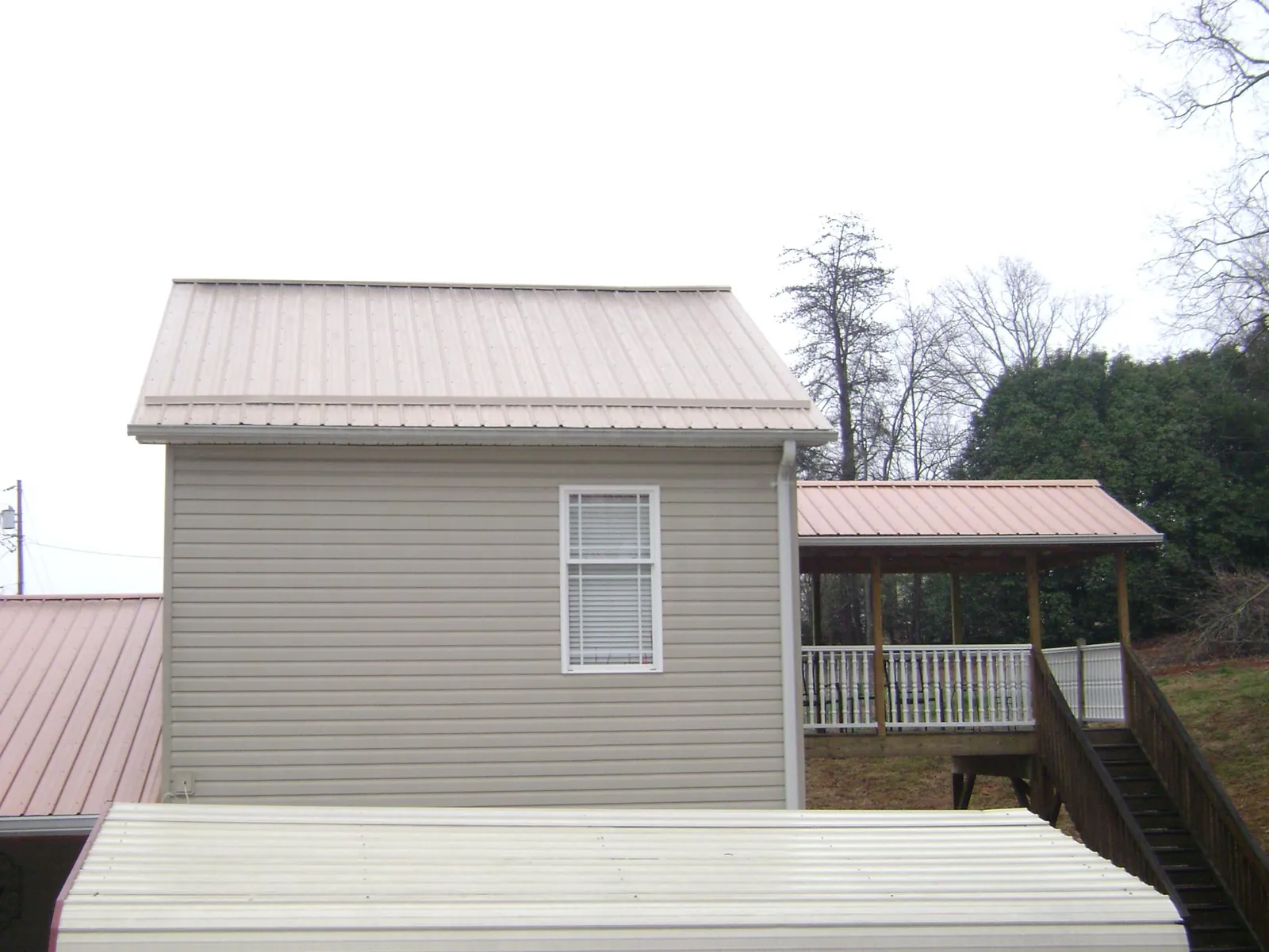 Tan metal roofs on a two story addition and attached porch, from a Roof Replacement job in Hermanville