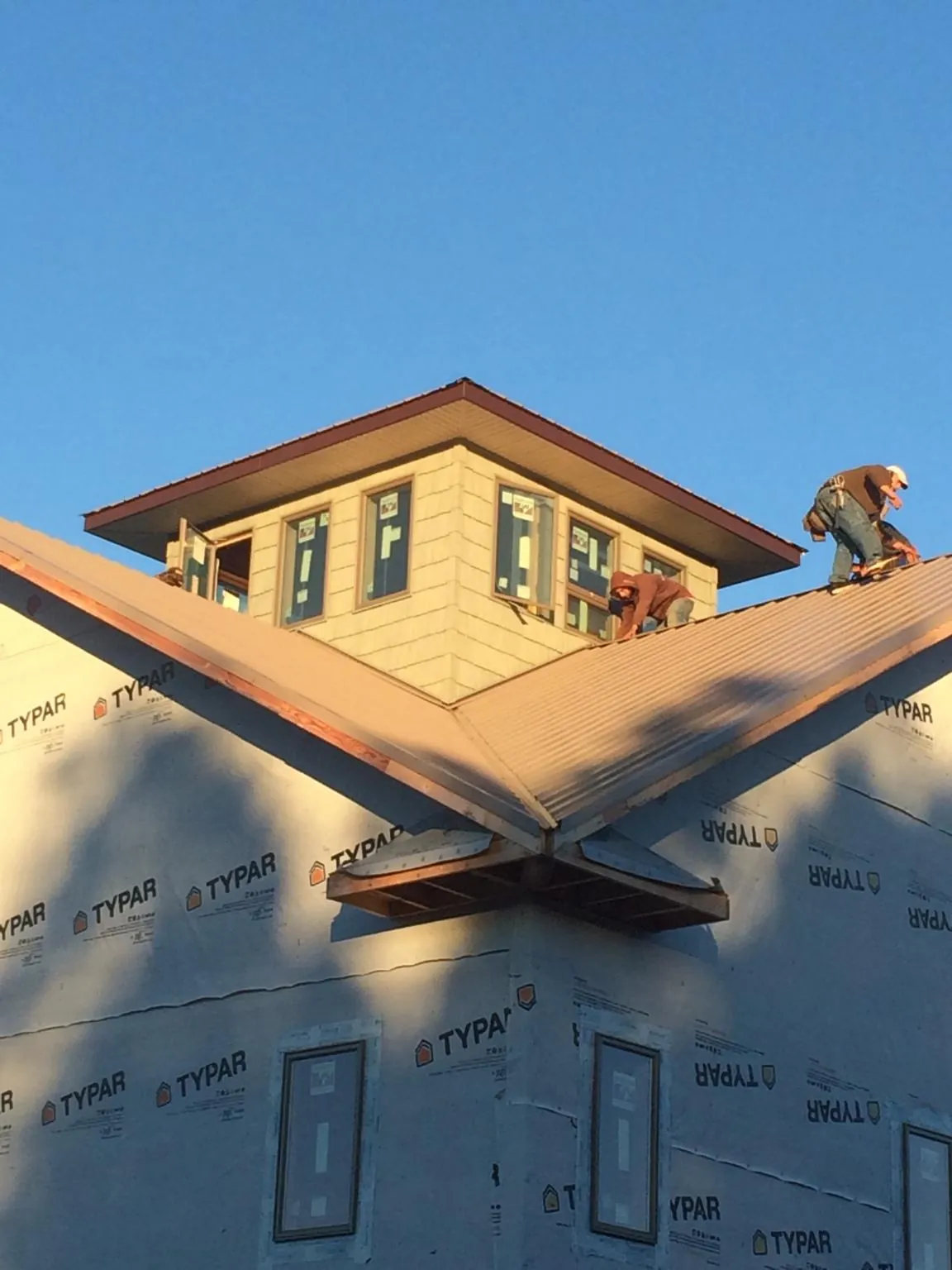Roofers working around a rooftop cupola on a new metal roof at sunset — Roof Waterproofing in Hermanville by Roofing Brothers